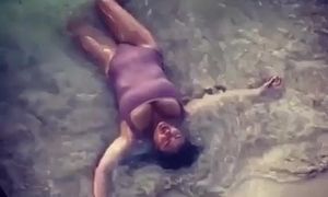 Salma Hayek laying in water on the beach